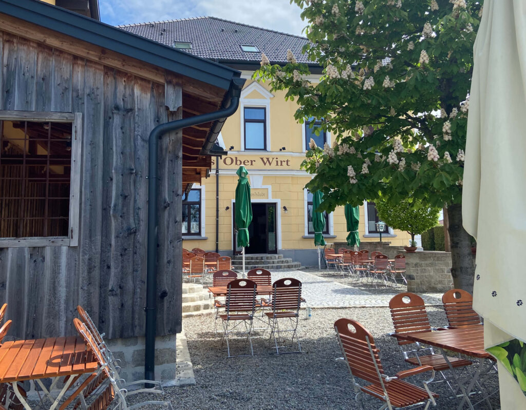 Auf dem Bild sieht man den Oberwirt Lambrechten. Hier werden täglich Ronis Schmankerl von Michelle Siegesleitner gekocht. Man sieht auf dem Bild den Gastgarten des Oberwirt. Auch hier bekommst du typische Österreichisches Essen in der Nähe.